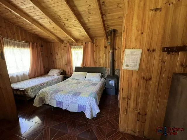 Dormitorio con camas, salamandra y vigas de madera a la vista en Mi Casa