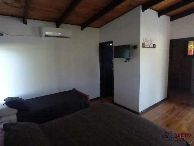 Living luminoso con sofás, TV y aire acondicionado en cabaña Mi Casa